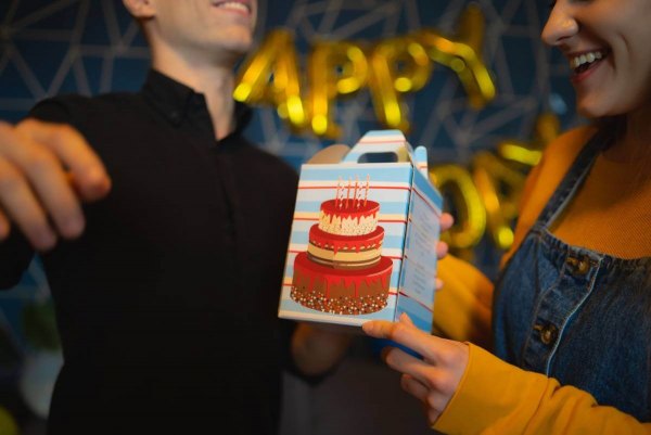Man holding birthday cake box, colourful patterned socks for a birthday person