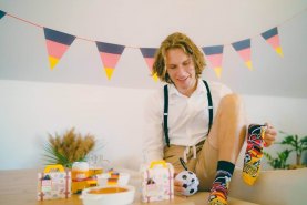 Mann hält Fußballsockenball und trägt nationale Sockenbox Deutschland, Socken für Männer