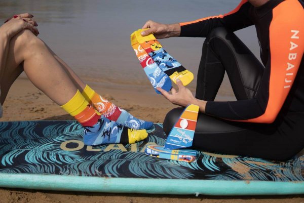 Frau trägt Windsurfing-Socken, Männer halten ein Paar Socken, Rainbow Socken