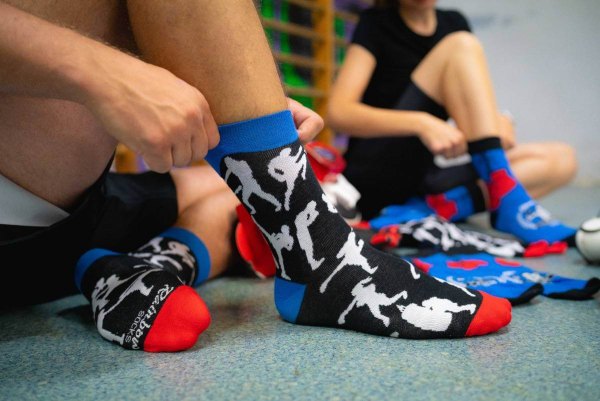 Mann und Frau probieren Socken mit Boxhandschuhen an, bunte Baumwollsocken, Socken, die wie Boxhandschuhe aussehen