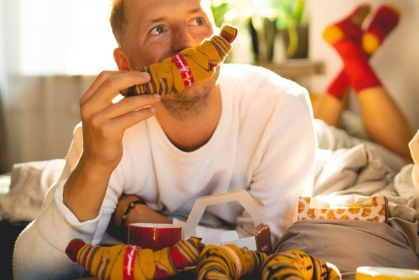 man holding and trying to eat raspberry croissant cotton socks, 1 pairof socks