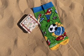 1 para zielonych skarpetek w brazylijskie wzory leżąca obok skarpetkowej walizki na prezent dla podróżnika, Rainbow Socks