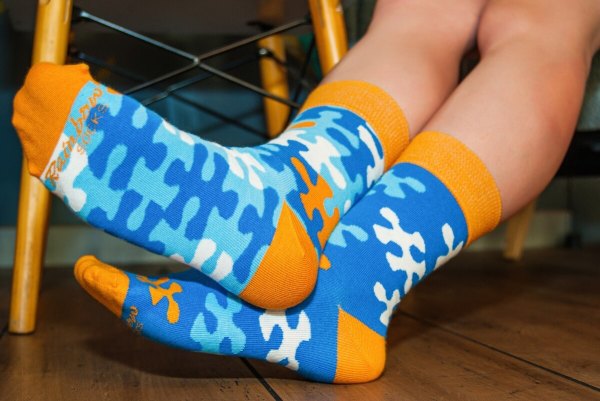 Frau trägt blaue und orangefarbene Socken mit Puzzlemotiven, Rainbow Socken