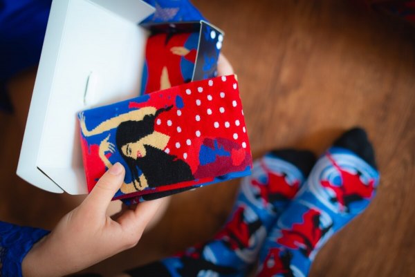 Woman opening Dance With Me Socks for a dancer, red socks with dance motifs