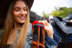 Kobieta trzymająca długie skarpetki kapelusz kowbojski Dziki Zachód, skarpetki na prezent