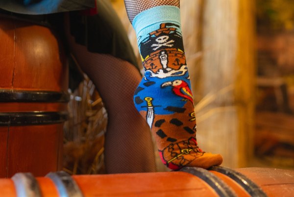 Woman wearing brown cotton socks with pirate patterns, gift idea for a seawolf, Rainbow Socks