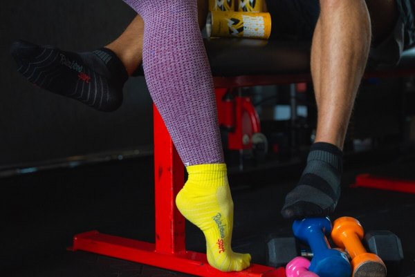 Frau in gelben Sportsocken und Mann in schwarzen Sportsocken, Energy-Drink-Socken in einer Dose als Geschenk für einen Sportfan