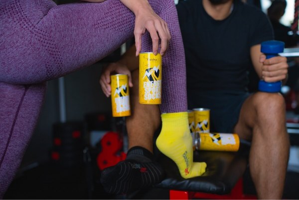 Frau trägt gelbe Sportsocken und hält Energy-Drink-Socken in einer Dose, Geschenk für einen Fan von Sport