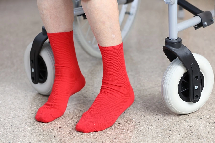 An elderly woman wearing red cotton compression-free socks for people struggling with circulation problems.