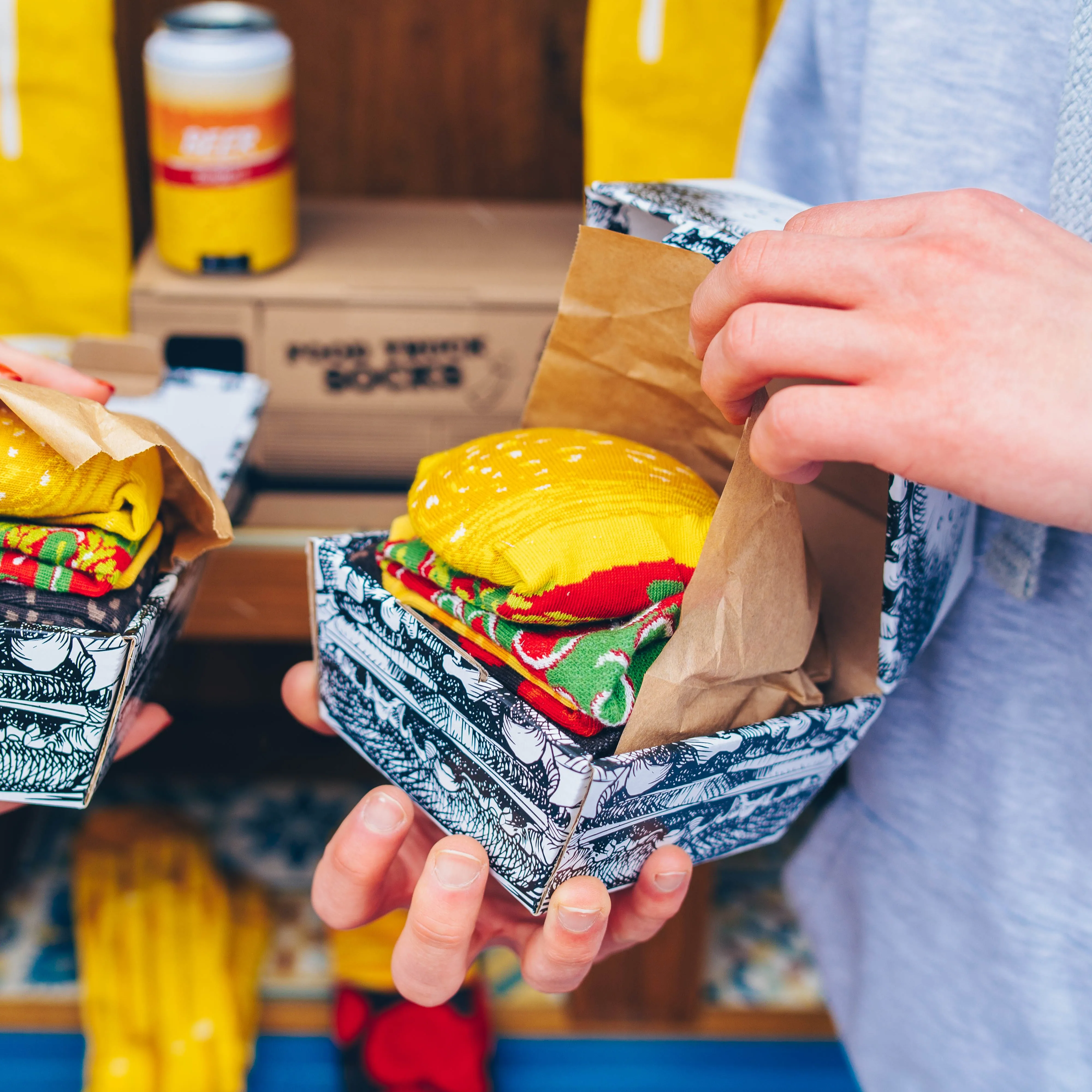 A man holding Rainbow Socks' burger socks in his hands.