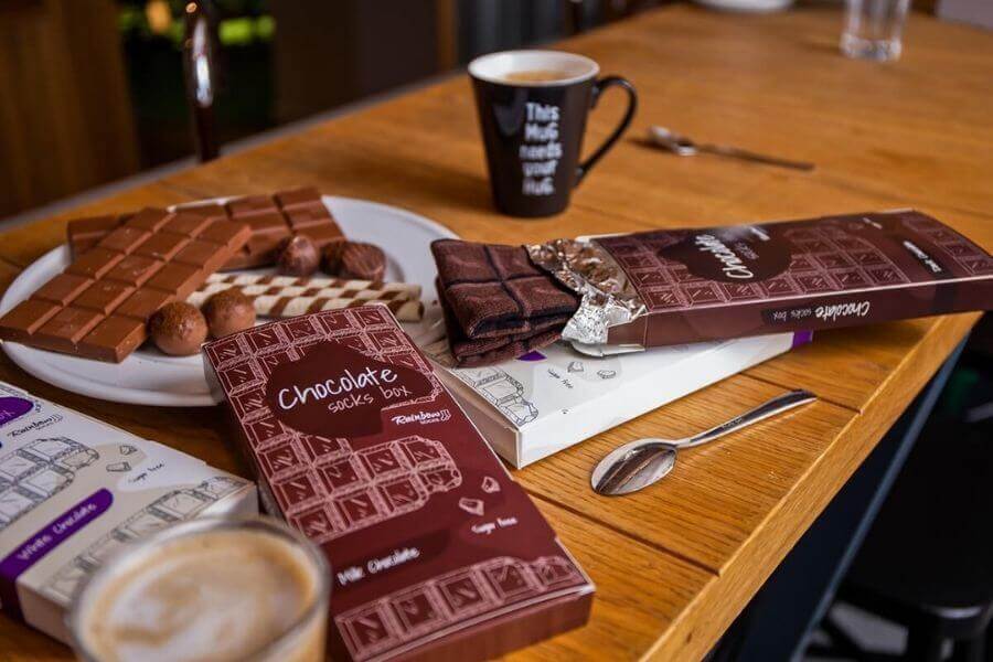 Socks resembling dark chocolate bar – table, mug, spoons 