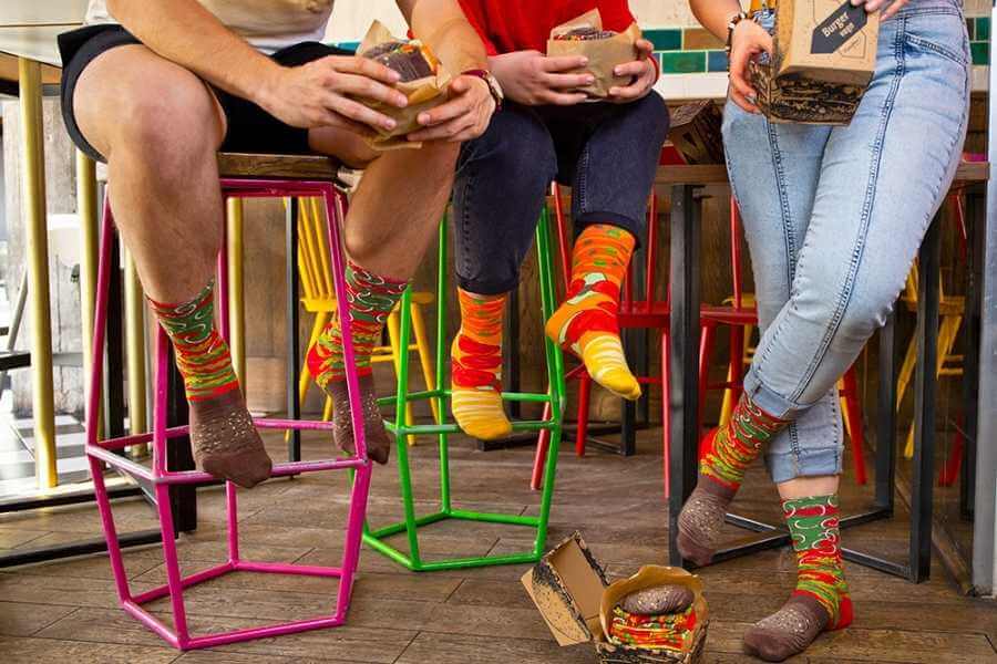 A group of men eating vegan food, wearing Rainbow Socks products