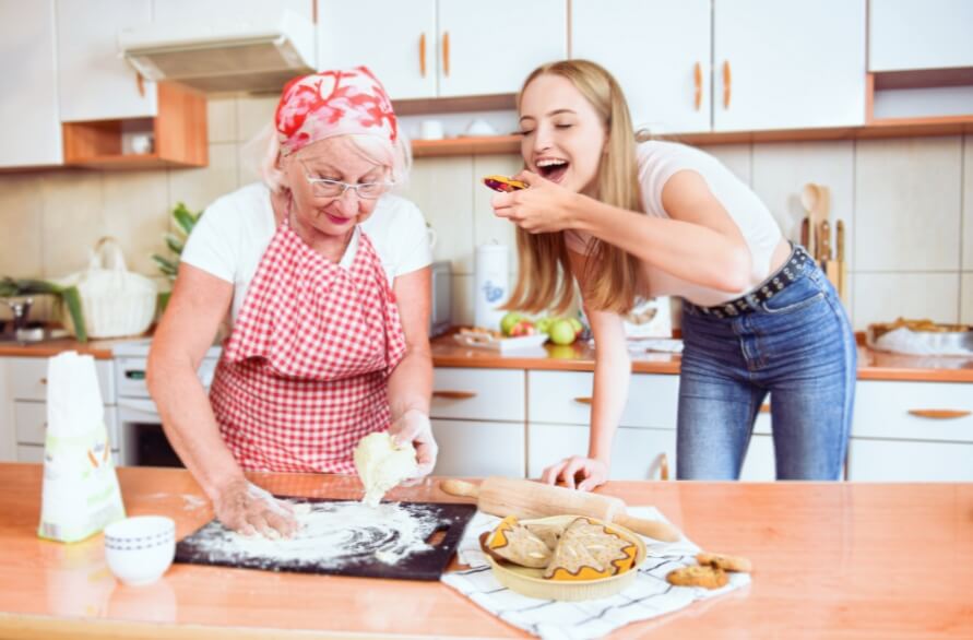 Two women, young and elder, are baking in the kitchen, next to them are dessert-themed socks from Rainbow Socks