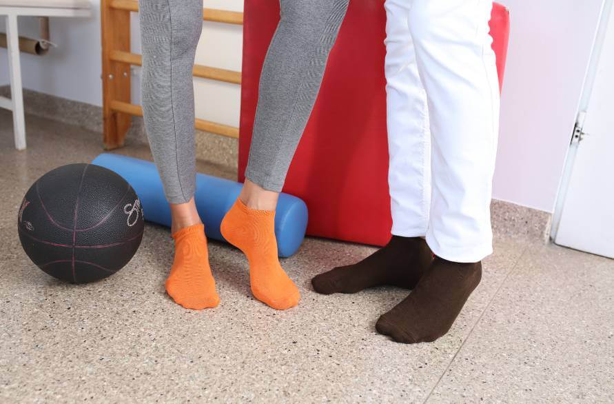 Two people in a sports hall wearing Rainbow ankle sports socks