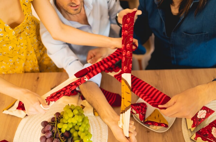 Drei Personen an einem Tisch, die Paare von Socken mit einem Käsekuchenmuster präsentieren.