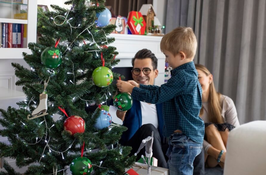 The parents and son decorate the Christmas tree with ornaments made from Rainbow Socks