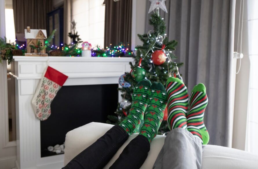 Two people in a festively decorated room wearing holiday socks
