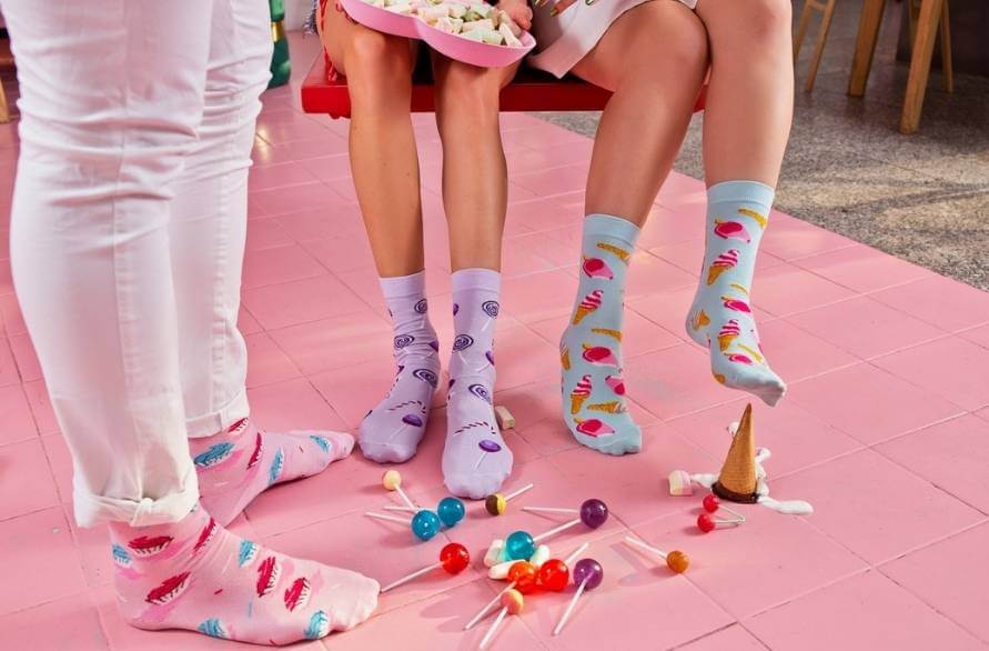 Three people wearing Sweet Socks with sweets scattered on the floor