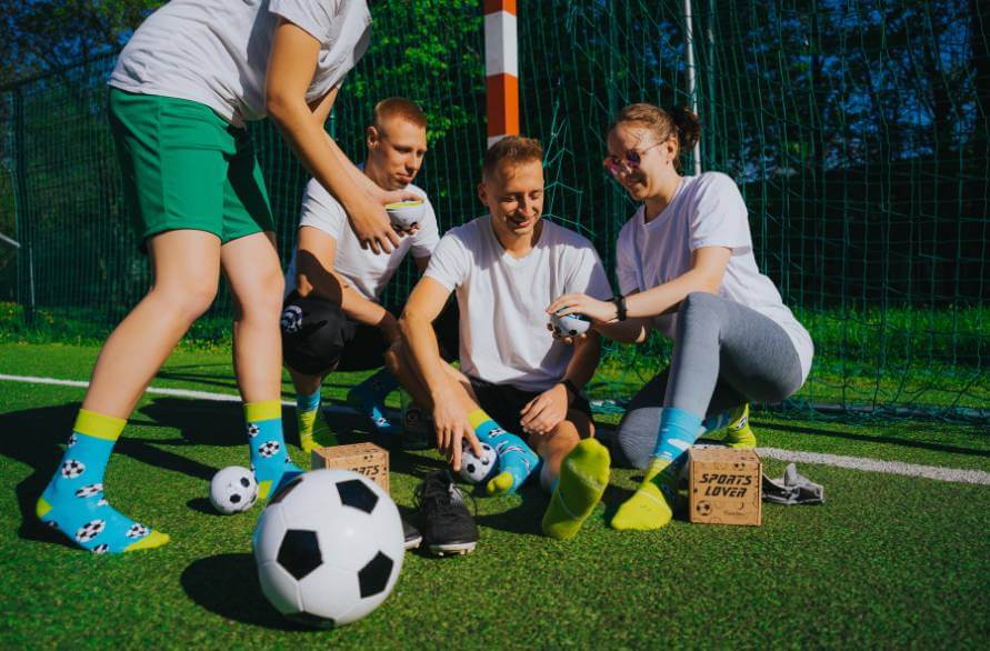 Grupa młodych ludzi na boisku piłkarskim w piłkarskich skarpetkach Rainbow Socks.
