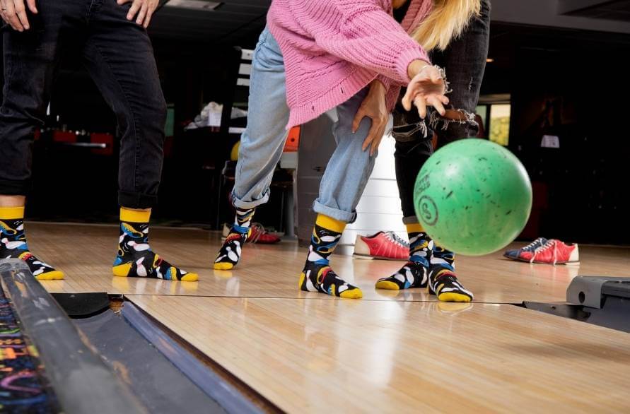 Three people wearing Fun Socks and bowling