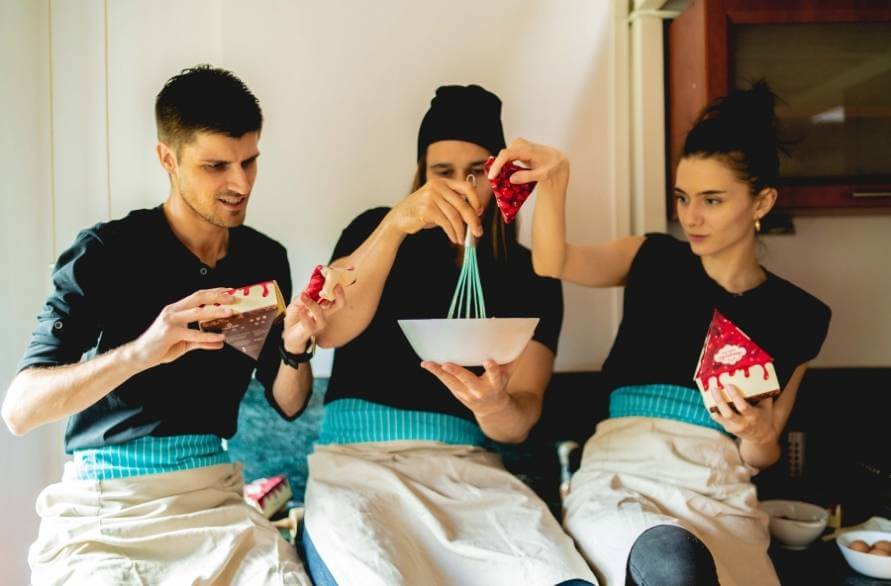Three people making a cake together holding a cheesecake Rainbow Socks set in their hands.