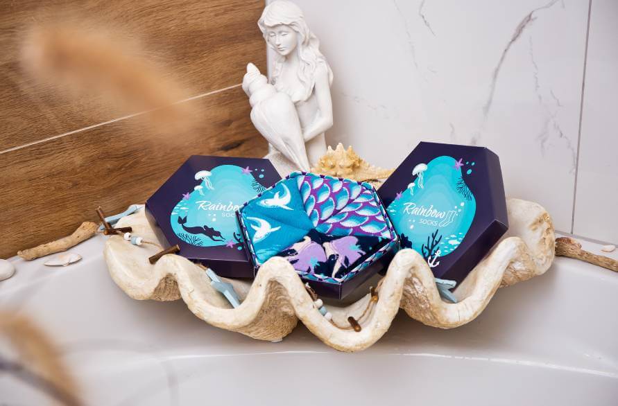 Three boxes of mermaid socks on a decorative tray with a mermaid figurine.