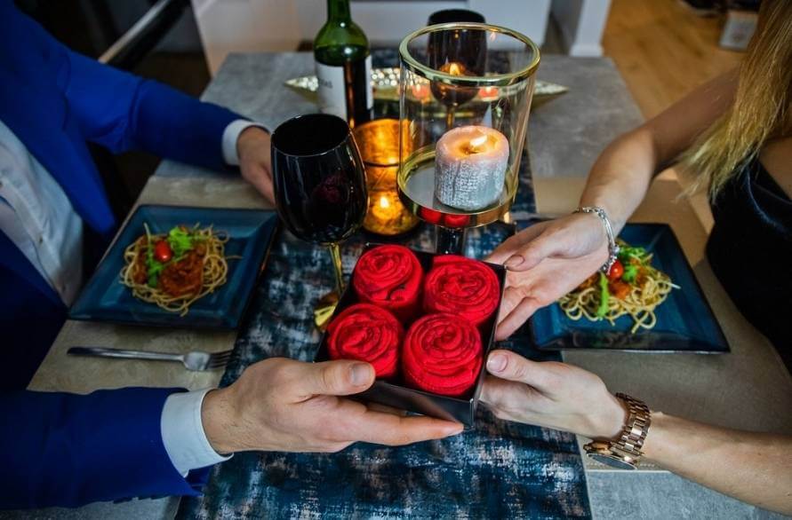 Kobieta i mężczyzna na romantycznej kolacji podarowujący sobie skarpetki w formie róż.