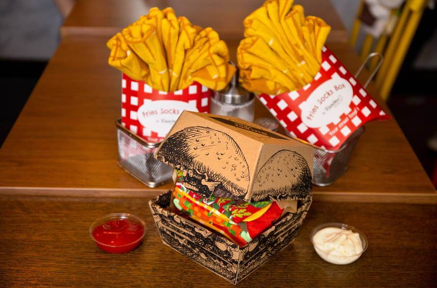 Rainbow burger socks and two packs of Rainbow fries socks on a table.